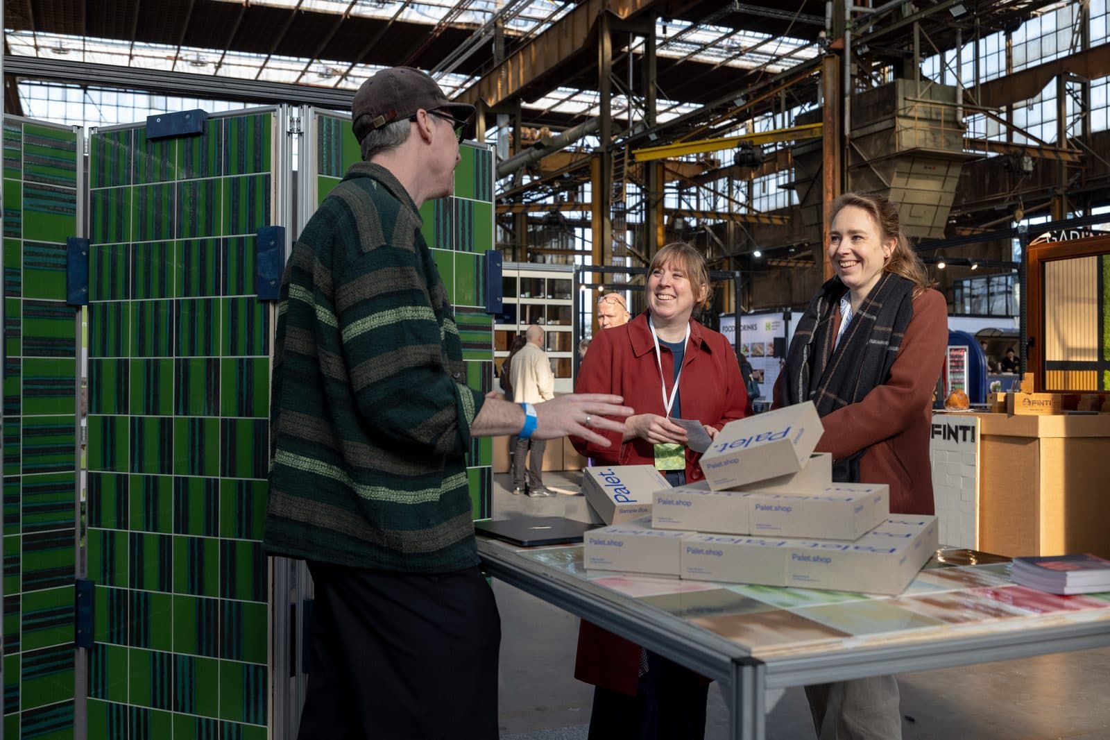 Three people in conversation at a stand at MaterialDistrict Utrecht.