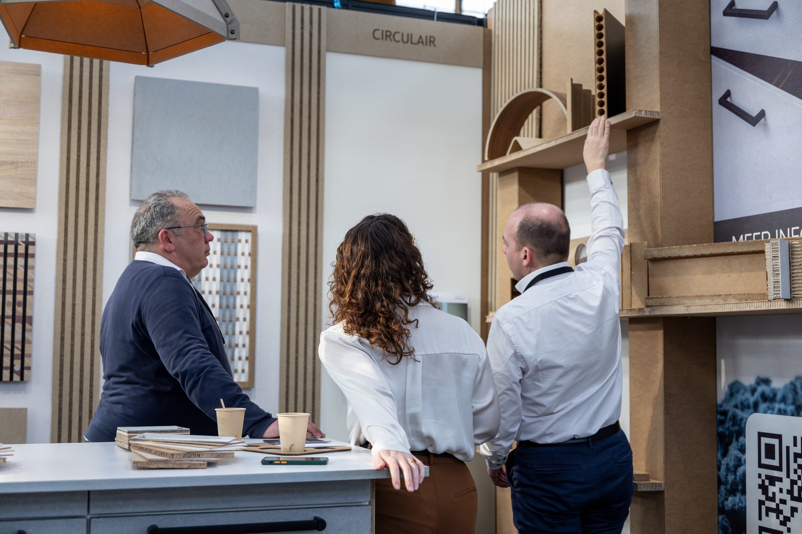 Three people discussing circular building materials at a stand marked “circulair”.