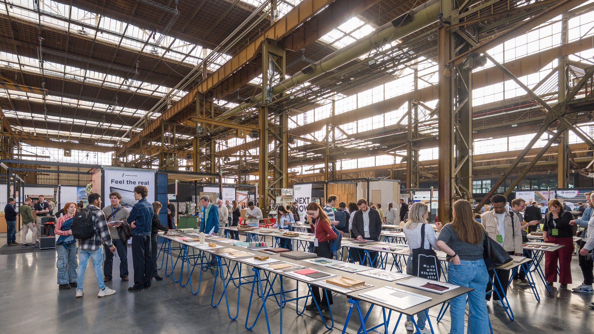Visitors browsing long tables of material samples in the Werkspoorkathedraal.