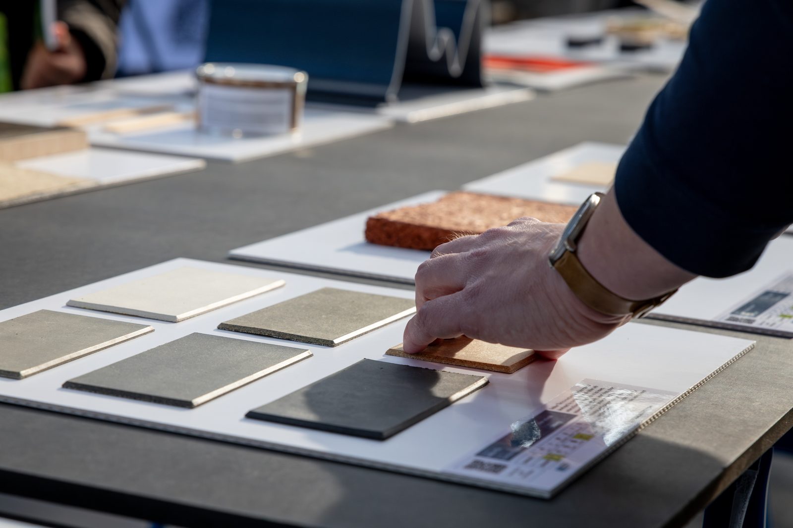 A visitor picks up a material sample from a table of samples.