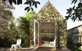 3D printed cabin of various materials has plants integrated in the façade